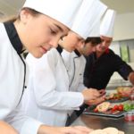 Equipe de cuisine en train de travailler, composée d'une cuisinière et deux cuisinier.