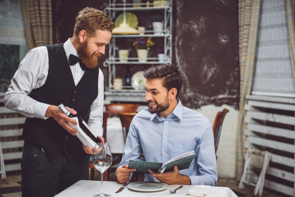 le sommelier présente une bouteille à son client souriant