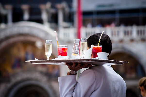 un serveur apporte un plateau sur lequel est disposé des boissons